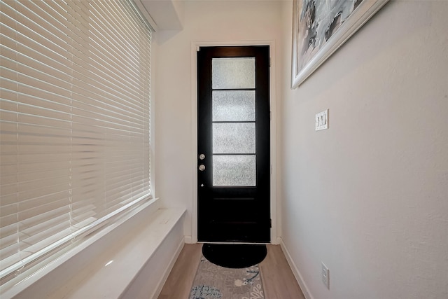 doorway to outside featuring baseboards and wood finished floors