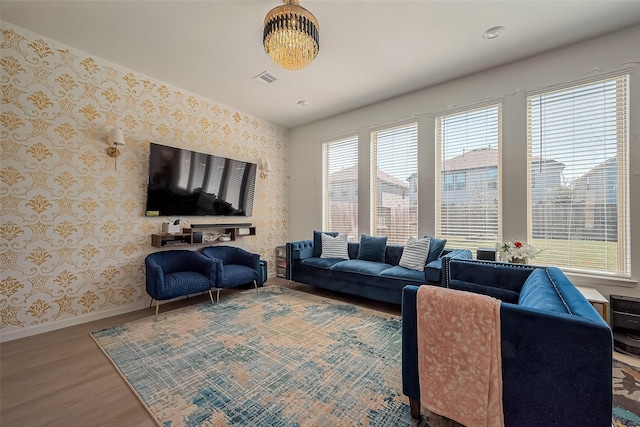 living area with visible vents, wallpapered walls, baseboards, and wood finished floors