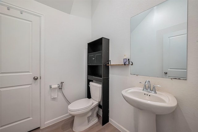 half bath with toilet, baseboards, and wood finished floors