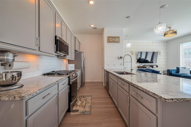 kitchen with visible vents, gray cabinets, a sink, appliances with stainless steel finishes, and a peninsula