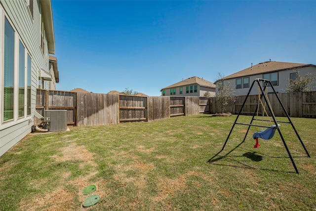 view of yard featuring central AC unit, a playground, and a fenced backyard