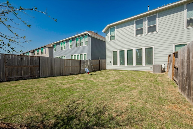 back of house featuring a yard, central AC unit, and a fenced backyard