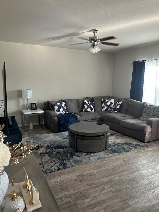 living room with a textured ceiling, wood finished floors, and a ceiling fan