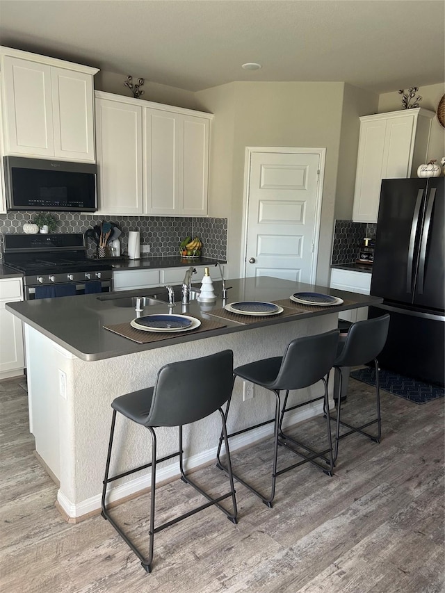 kitchen featuring dark countertops, stainless steel gas range, light wood-style floors, and freestanding refrigerator