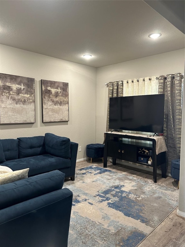 living room featuring a textured ceiling, wood finished floors, and baseboards