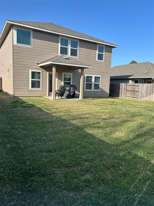 rear view of property with a patio, a lawn, and fence