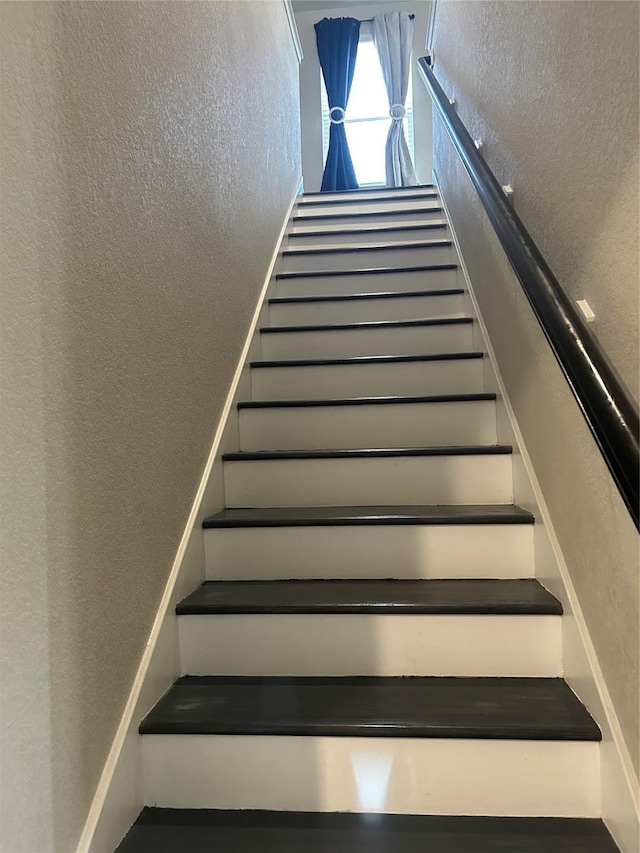 stairway featuring a textured wall