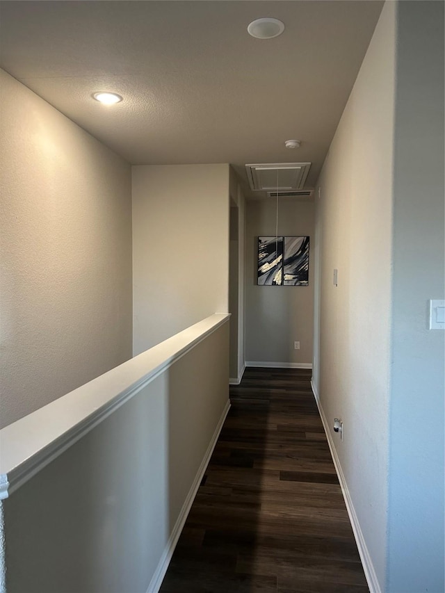 hallway with dark wood finished floors, attic access, and baseboards