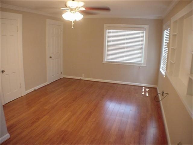 unfurnished room featuring ceiling fan, ornamental molding, wood finished floors, and baseboards