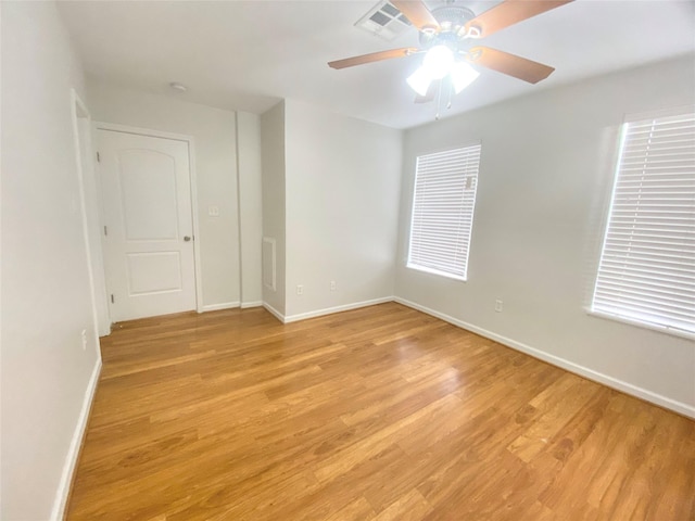 empty room with light wood-style flooring, visible vents, baseboards, and ceiling fan