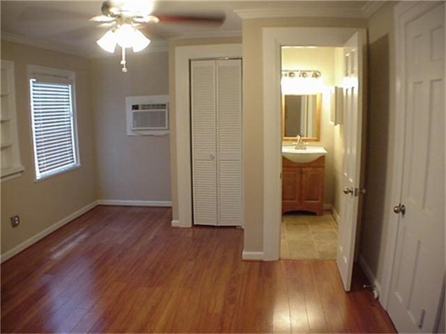 unfurnished bedroom featuring a sink, light wood-style flooring, crown molding, and a wall mounted AC