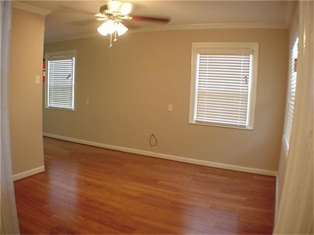 empty room featuring ceiling fan, ornamental molding, wood finished floors, and baseboards