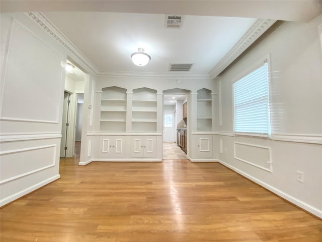 interior space with light wood-style floors, visible vents, and crown molding