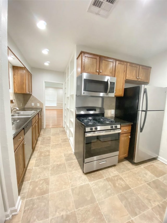 kitchen with tasteful backsplash, visible vents, dark countertops, appliances with stainless steel finishes, and a sink