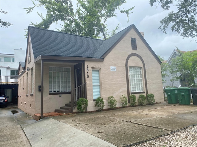 view of front of house featuring entry steps, a shingled roof, and brick siding