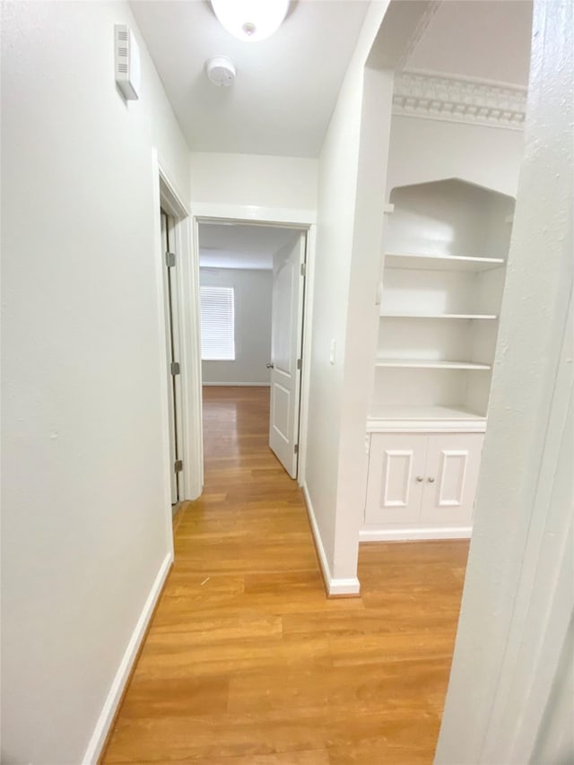 corridor featuring light wood-type flooring and baseboards