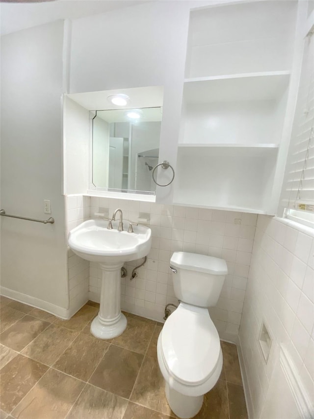 bathroom with a sink, toilet, and tile walls