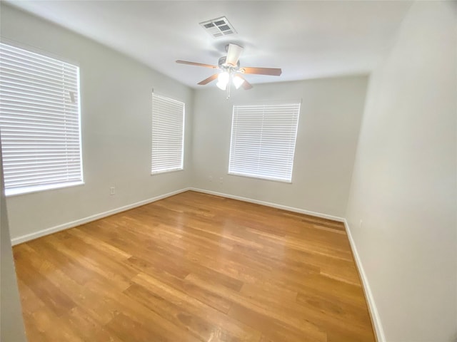 unfurnished room with baseboards, a ceiling fan, visible vents, and light wood-style floors