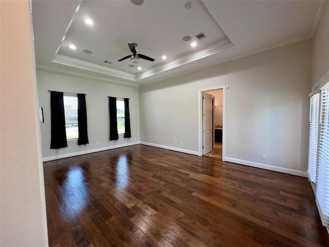 spare room featuring dark wood finished floors, a raised ceiling, crown molding, and visible vents