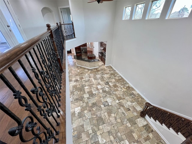 staircase with stone finish floor, a ceiling fan, and baseboards