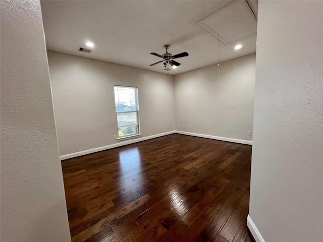 spare room featuring attic access, baseboards, dark wood-type flooring, and visible vents