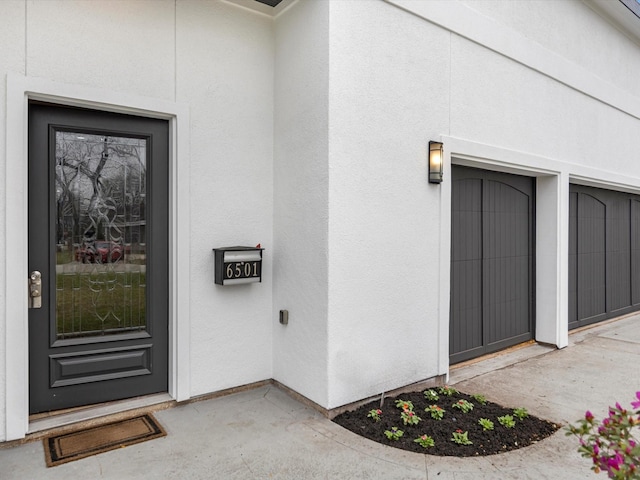 view of exterior entry featuring a garage and stucco siding