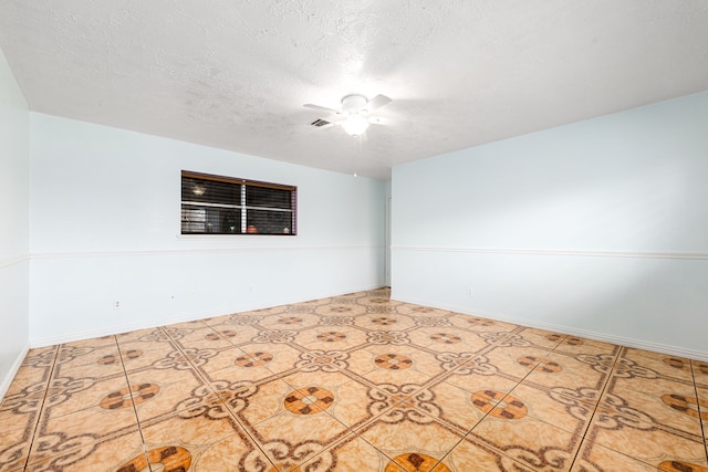 spare room featuring baseboards, a textured ceiling, and ceiling fan