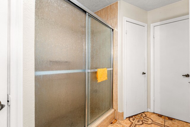 bathroom featuring tile patterned floors, a stall shower, and a textured ceiling