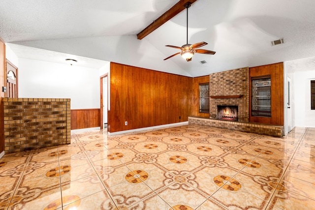 unfurnished living room with wooden walls, a wainscoted wall, visible vents, lofted ceiling with beams, and a textured ceiling