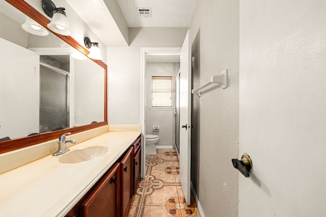 full bath with vanity, a shower with shower door, visible vents, tile patterned flooring, and toilet