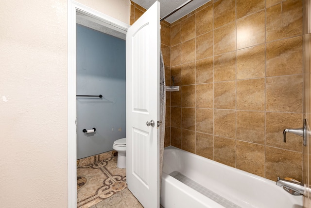 bathroom featuring tile patterned floors, toilet, and bathing tub / shower combination