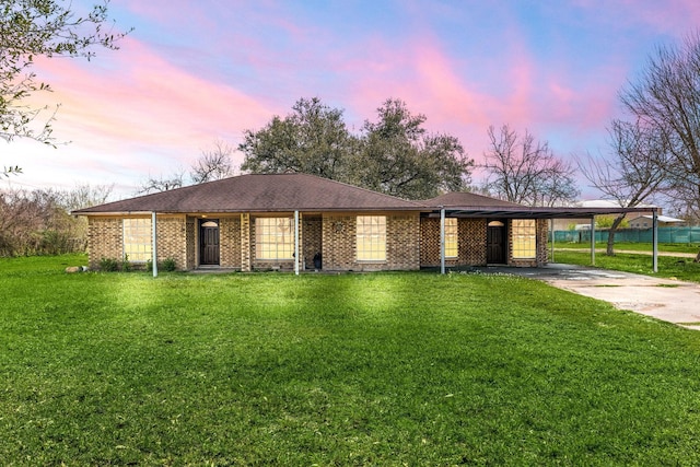 ranch-style home with brick siding, a lawn, driveway, and an attached carport