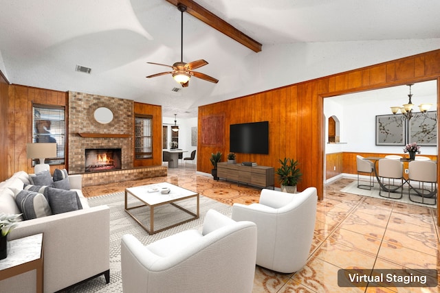 living area featuring wooden walls, visible vents, vaulted ceiling with beams, ceiling fan with notable chandelier, and a fireplace