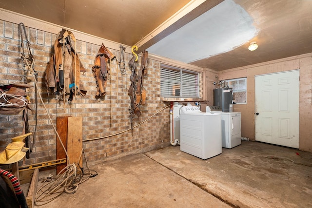 below grade area with electric water heater, brick wall, and washer and clothes dryer