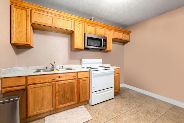 kitchen featuring stainless steel microwave, baseboards, white range with electric cooktop, light countertops, and a sink