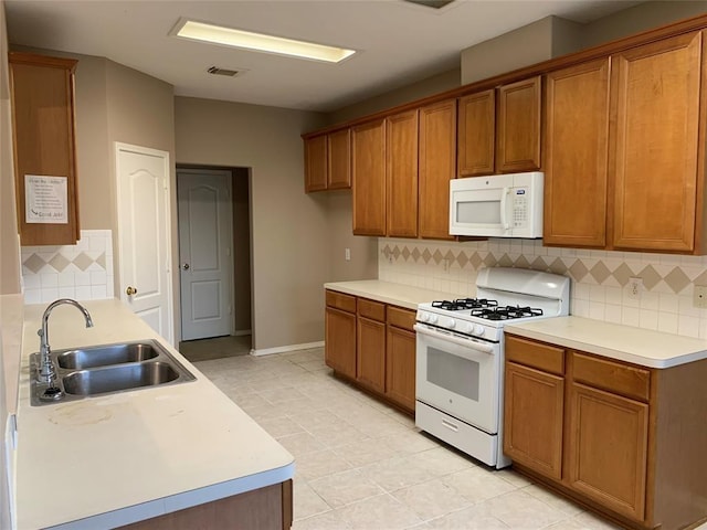 kitchen with white appliances, brown cabinetry, and a sink