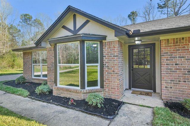 view of exterior entry featuring brick siding and a shingled roof