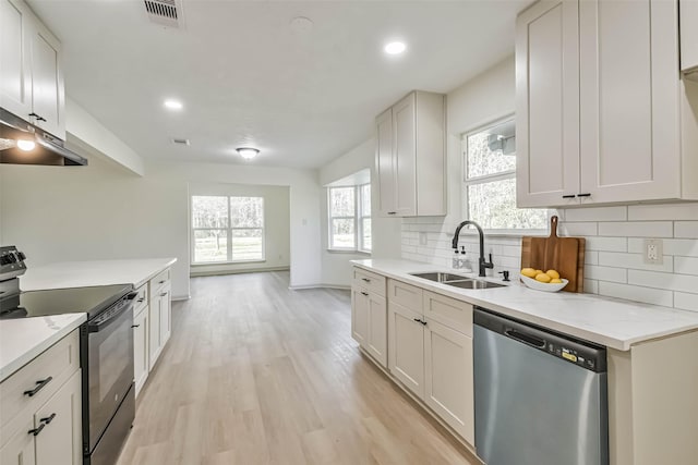 kitchen with black electric range, dishwasher, a sink, light wood-style floors, and tasteful backsplash
