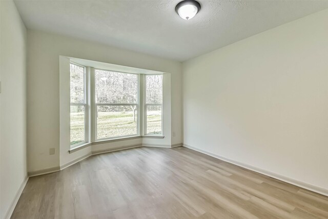 spare room featuring baseboards and light wood finished floors