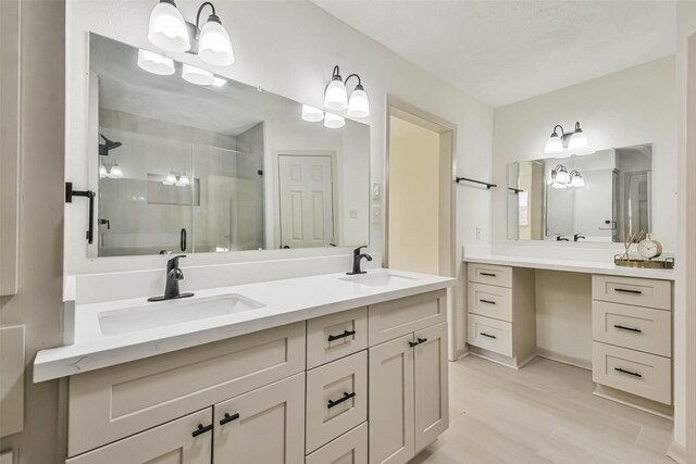 bathroom featuring a sink, wood finished floors, a stall shower, and double vanity