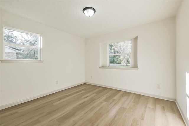 unfurnished room with baseboards and light wood finished floors