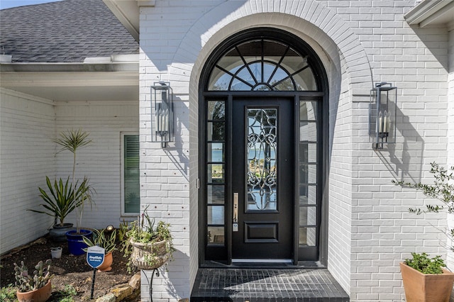 property entrance with brick siding and roof with shingles