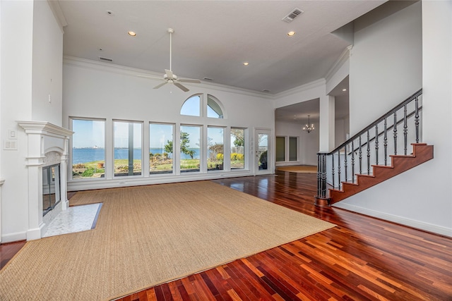 living area with ornamental molding, wood finished floors, a healthy amount of sunlight, and a premium fireplace