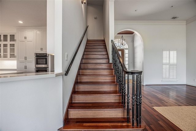 stairs with arched walkways, crown molding, recessed lighting, wood finished floors, and baseboards