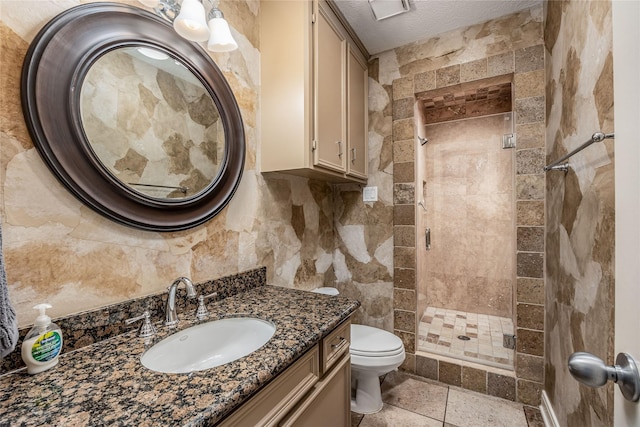 bathroom with tile walls, toilet, a stall shower, a textured ceiling, and vanity