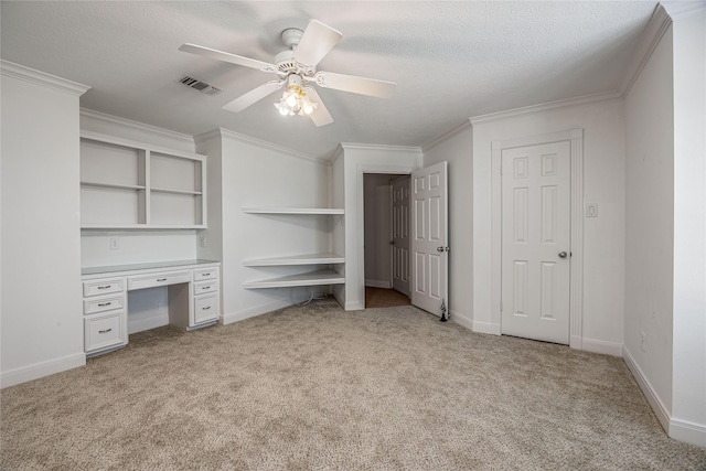 unfurnished bedroom featuring built in study area, visible vents, crown molding, and light colored carpet