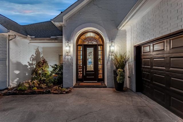 property entrance featuring brick siding and roof with shingles