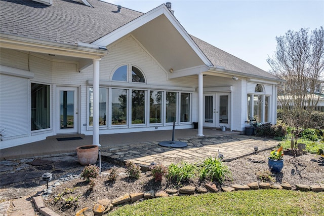 rear view of house with a patio area, a shingled roof, brick siding, and french doors