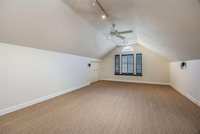 additional living space with light carpet, baseboards, ceiling fan, vaulted ceiling, and a textured ceiling