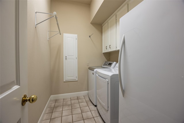 clothes washing area with washer and dryer, cabinet space, baseboards, and light tile patterned floors